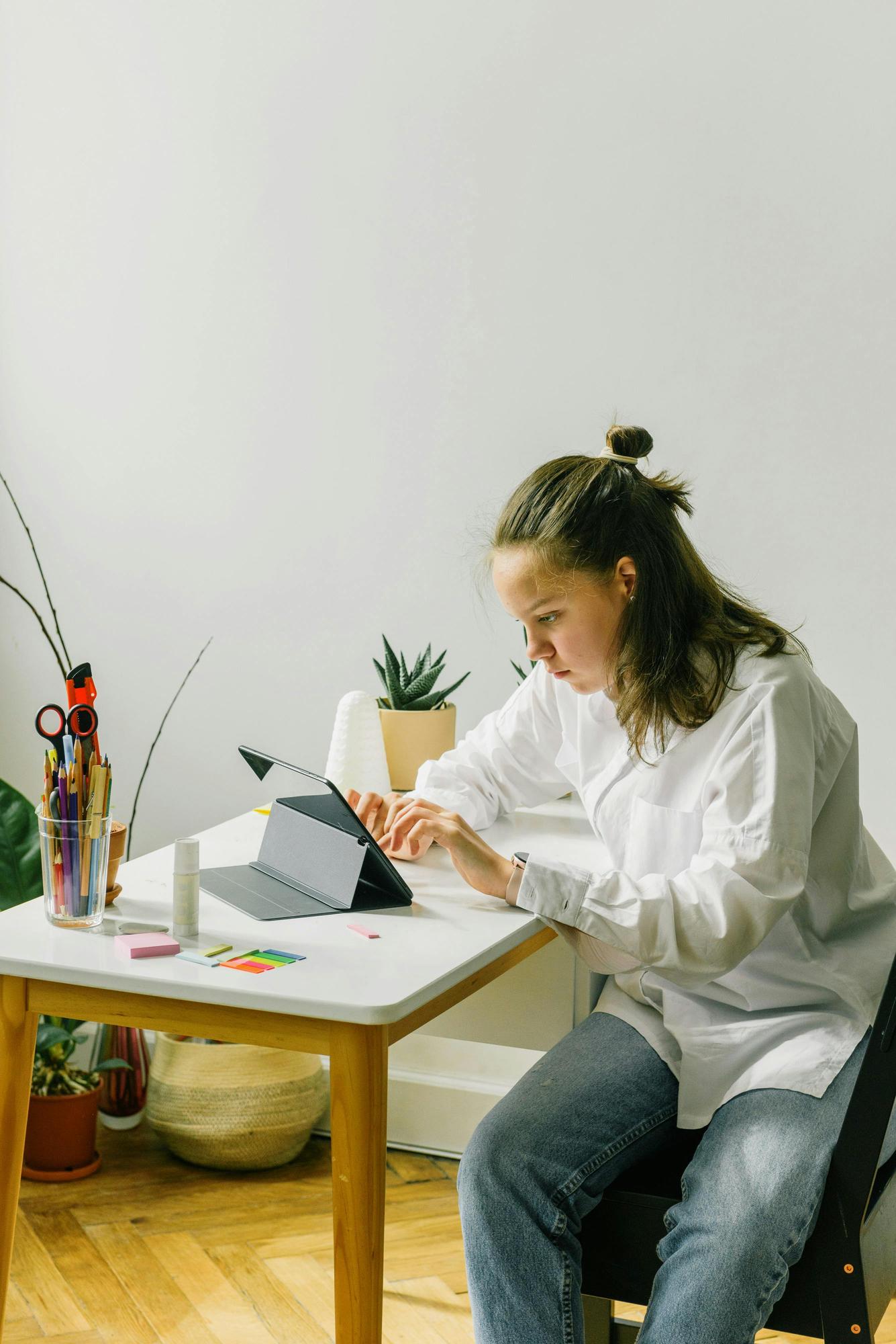 Studentė siuva ant hoop'o prie lango